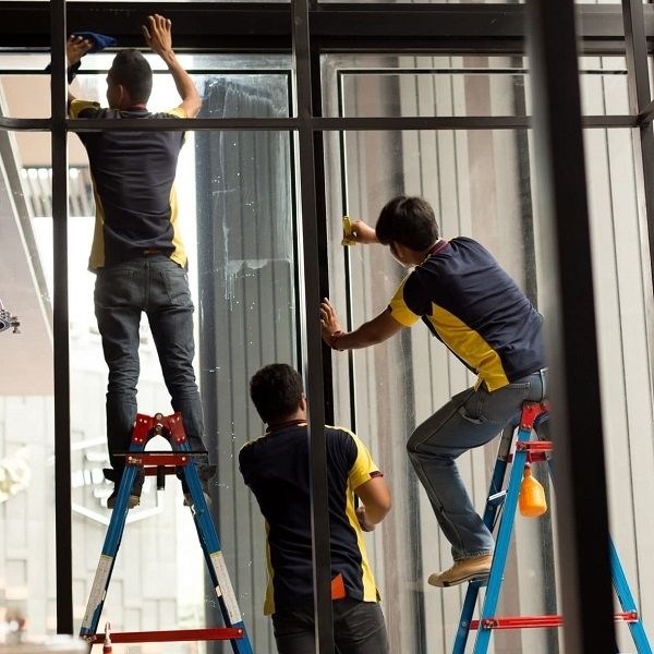 Technicians installing security window film to reinforce commercial glass.