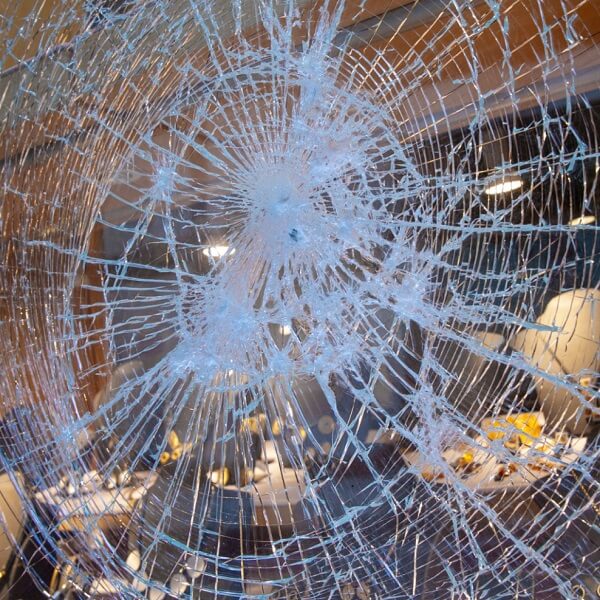 Shattered glass window with a central impact point, illustrating the damage from smash and grab crime.