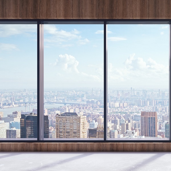 High-rise view of a vast city skyline through large windows, demonstrating the potential for DefenseLite secondary glazing to improve the energy efficiency of a commercial building envelope.