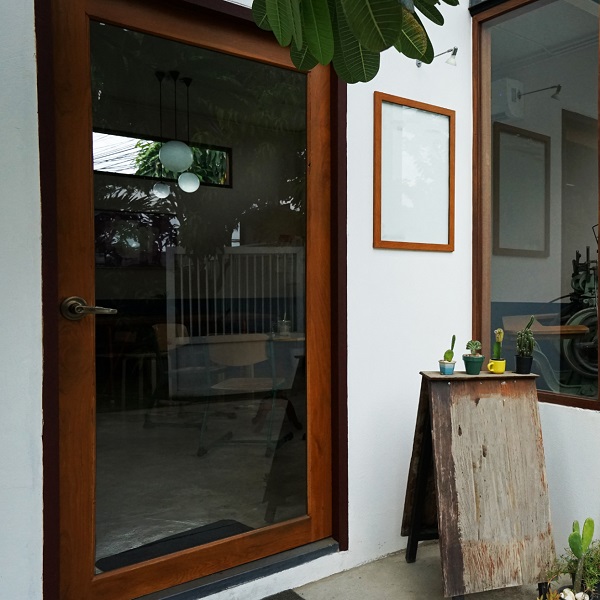 Close-up of a wooden-framed glass entrance door and window of a cafe or shop, suggesting noise minimization through soundproofing architecture.