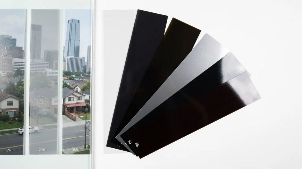 The image showcases various samples of high-quality window film, each demonstrating different tint levels and reflective properties designed for heat control and energy efficiency. These films effectively block the sun's heat and harmful ultraviolet rays while maintaining visibility and allowing natural light to enter, making them ideal for enhancing indoor comfort and reducing cooling costs.